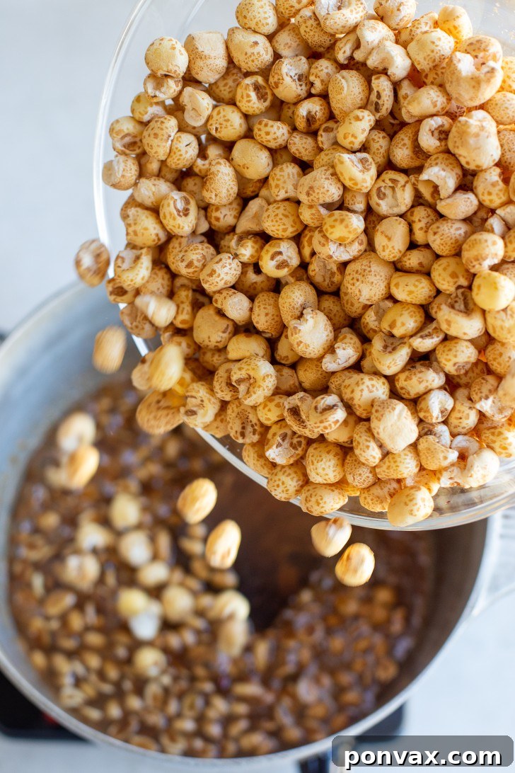Maple Peanut Puffed Corn mixture spread on a parchment-lined baking sheet