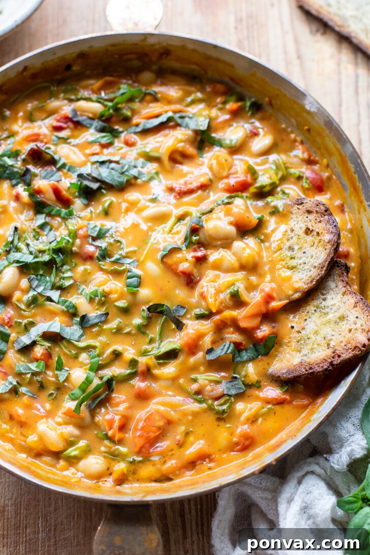 Velvety Tomato and Cannellini Stew 2 A vibrant bowl of Creamy Tomato White Bean Stew garnished with fresh basil.