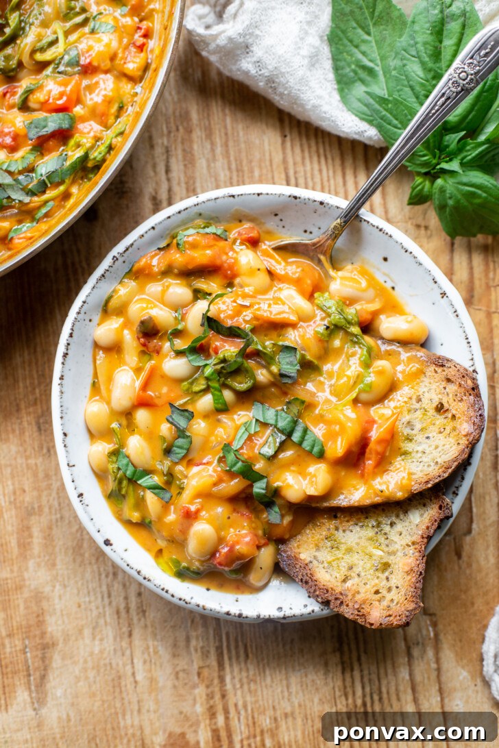 Velvety Tomato and Cannellini Stew 13 Final creamy tomato white bean stew in the pan with lemon wedge.