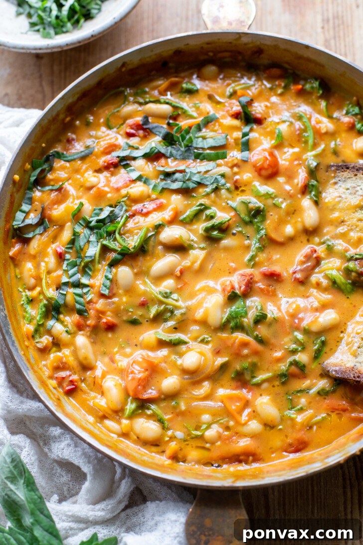Velvety Tomato and Cannellini Stew 5 A bowl of creamy vegan tomato white bean stew with fresh basil, ready to be served.