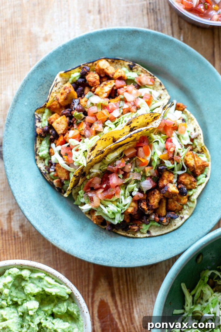 A vibrant spread of vegan black bean tofu tacos, surrounded by fresh ingredients and toppings.