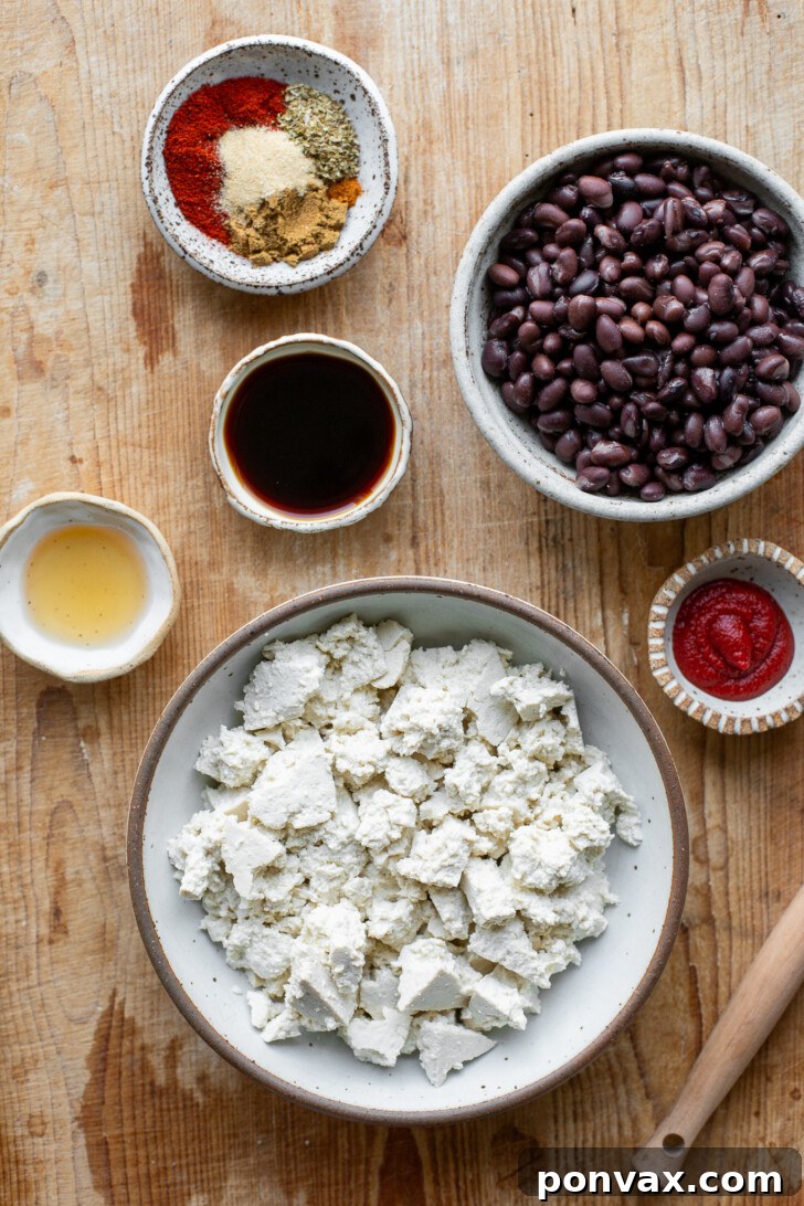 Various ingredients for vegan tofu black bean tacos, including black beans, crumbled tofu, and spices, laid out on a kitchen surface.