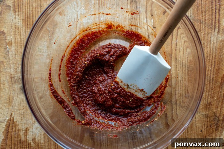 Crumbled tofu and black beans being mixed with the spice paste in a bowl.