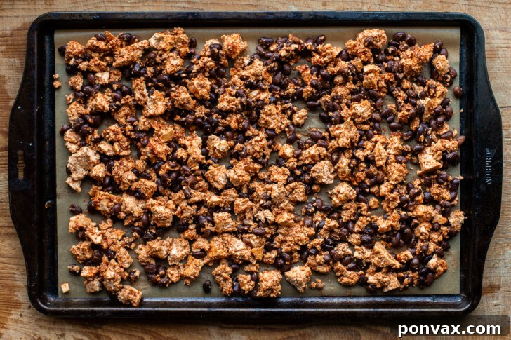 Tofu and black bean mixture spread evenly on a parchment-lined baking sheet.