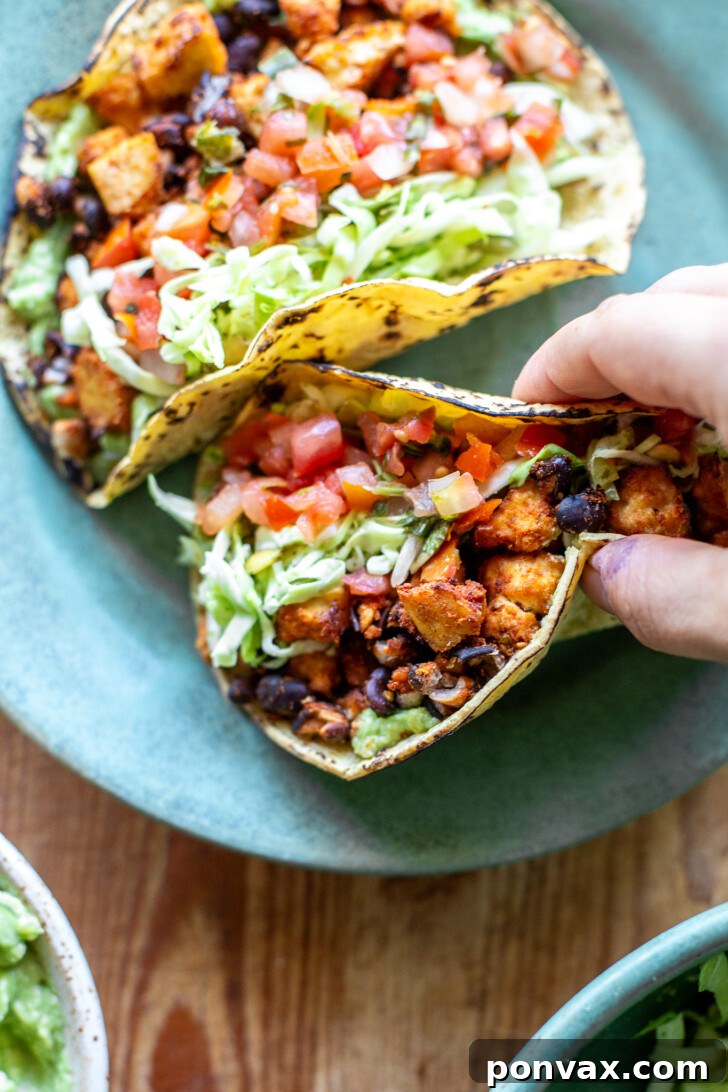 Fully assembled Vegan Tofu Tacos with black bean chorizo, guacamole, cabbage slaw, and fresh lime wedges.