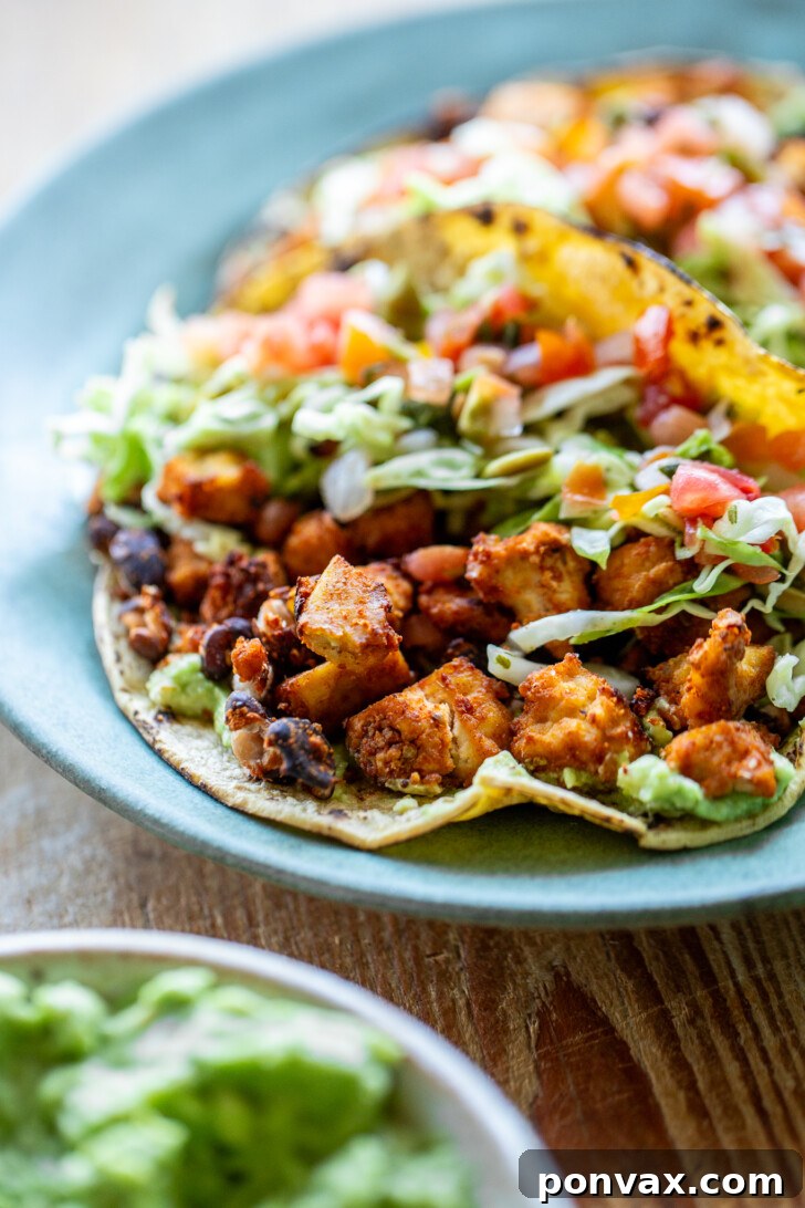 A close-up shot of vegan tofu black bean tacos, showcasing the vibrant filling and fresh toppings.