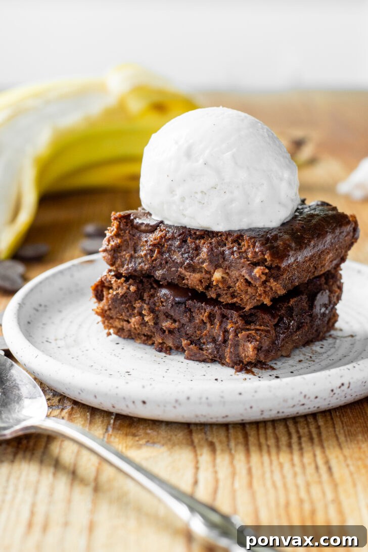 Fudgy Vegan Flourless Banana Brownies, garnished with chocolate chips, on a white surface.