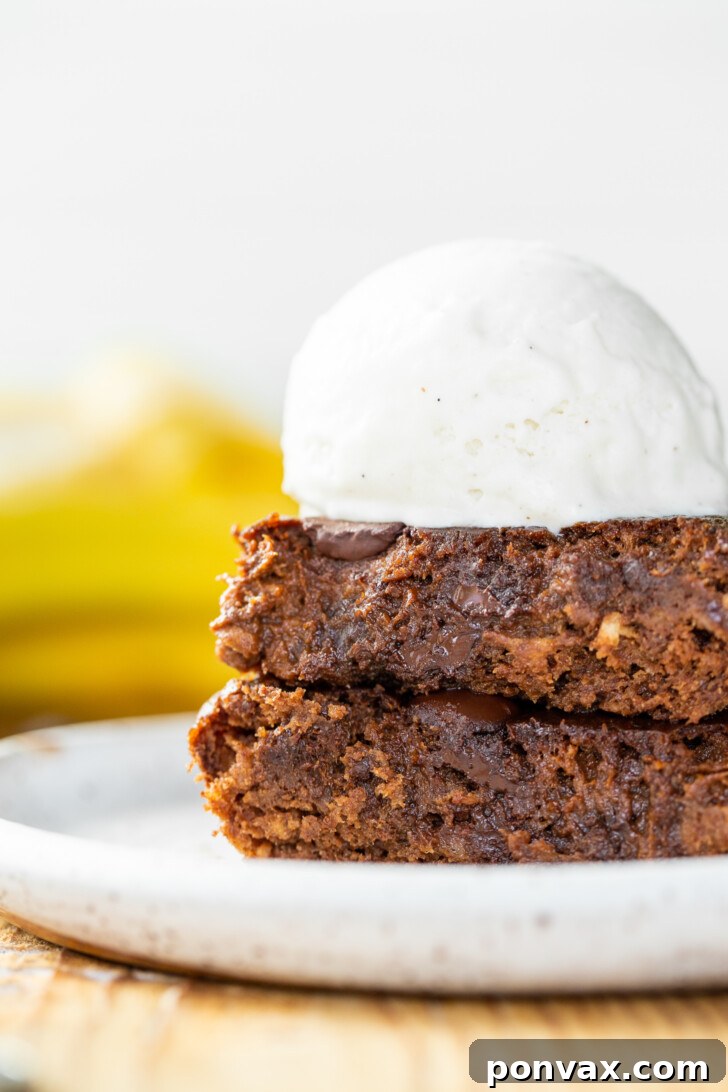 Close-up of a single Vegan Flourless Banana Brownie with a fudgy center and visible chocolate chips.