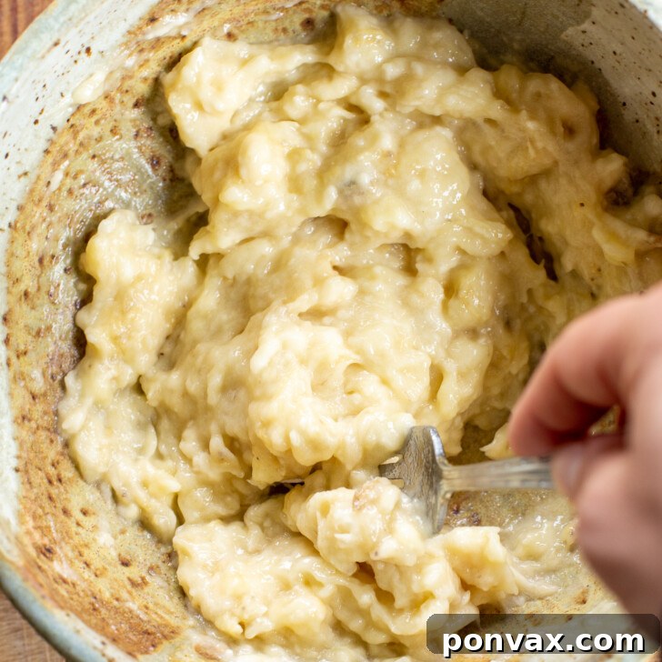 Mashing ripe bananas in a mixing bowl for brownie batter.