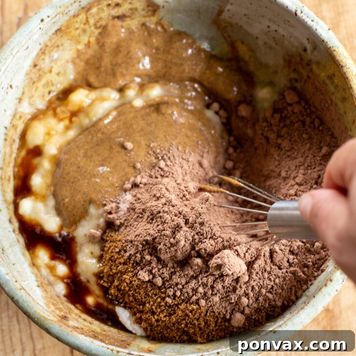 Adding all ingredients into a bowl with mashed bananas.