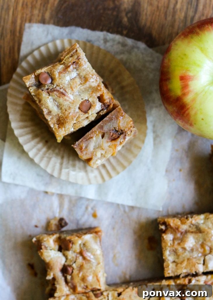 Individual Apple Cinnamon Blondie squares neatly stacked, showcasing their moist interior and the delightful texture of the baked apple chunks and cinnamon chips.