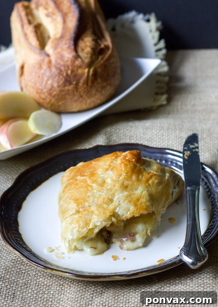 A golden-brown baked brie appetizer, elegantly wrapped in puff pastry and garnished with sweet brown sugar apples and pecans, ready to be served. This Brown Sugar Apple Baked Brie is filled with apples and pecans, all wrapped in puff pastry for the perfect delicious appetizer!