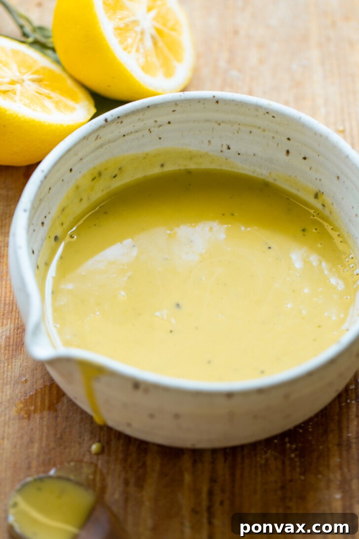 A bowl of creamy, bright yellow lemon vinaigrette, ready to be drizzled over dishes, highlighting its smooth texture and fresh appeal.