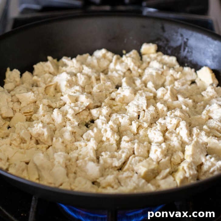 Step 1: Firm tofu being crumbled into a pan.