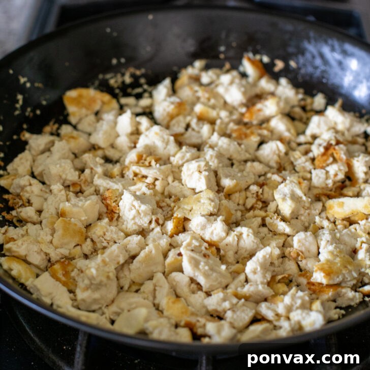 Step 2: Sautéing crumbled tofu in a pan until lightly browned.