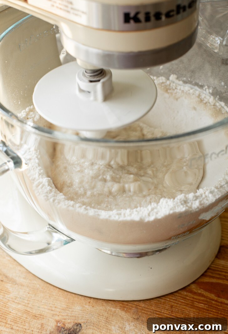 Gluten-free bread dough being kneaded by hand on a floured surface.