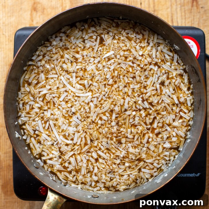 Tropical Coconut Elixir 6 The simmering coconut syrup mixture being stirred in a saucepan.