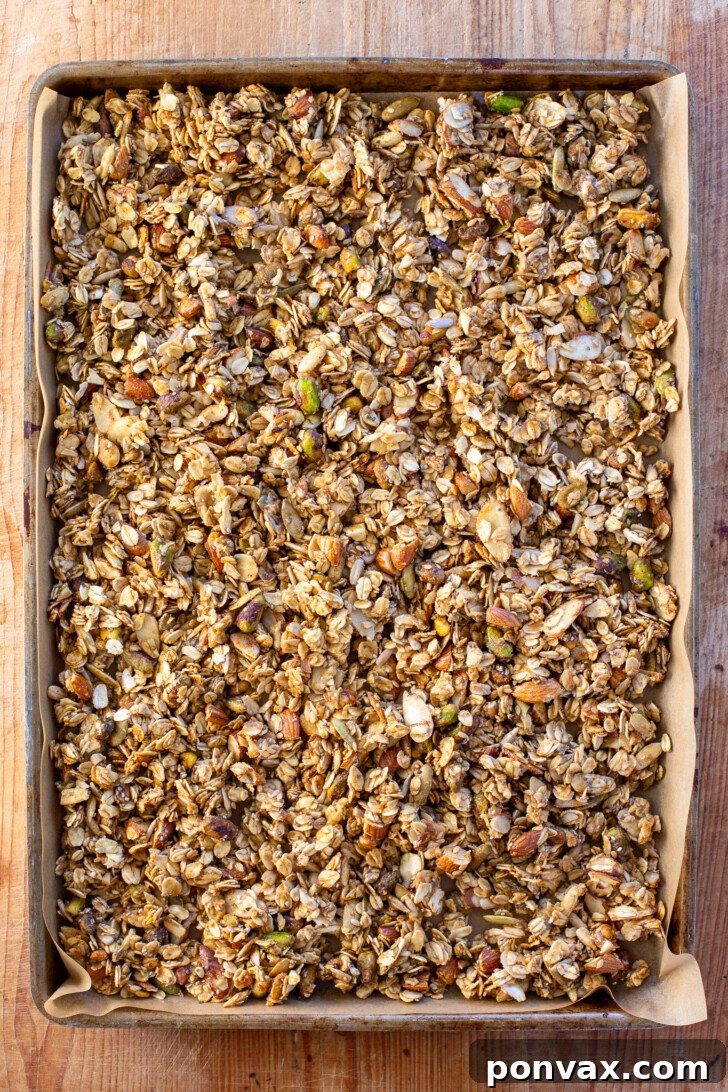 Freshly baked savory granola cooling on a baking sheet, forming clusters.