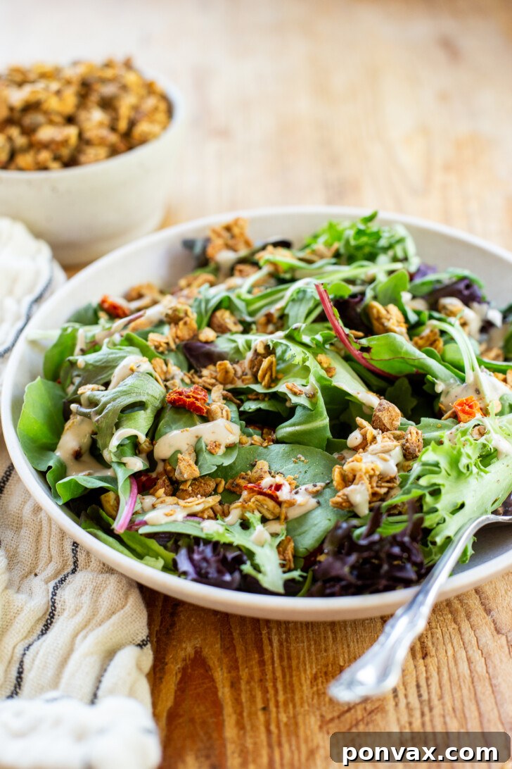 Savory granola sprinkled over a vibrant green salad, showcasing its use as a topping.