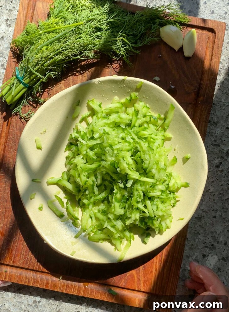 Dairy-Free Tzatziki Delight 4 Step-by-step image showing grated cucumbers being squeezed in a towel to remove excess moisture for tzatziki.