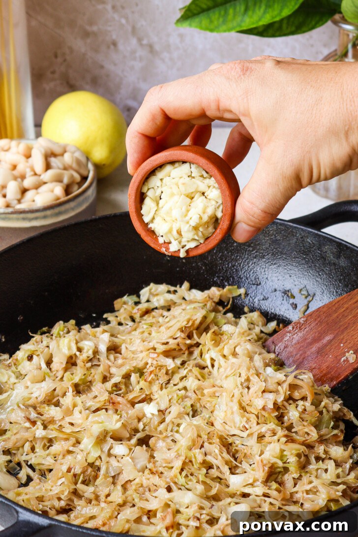 A culinary shot showing thinly sliced cabbage and diced shallots beginning to soften in a pan with vegan butter.