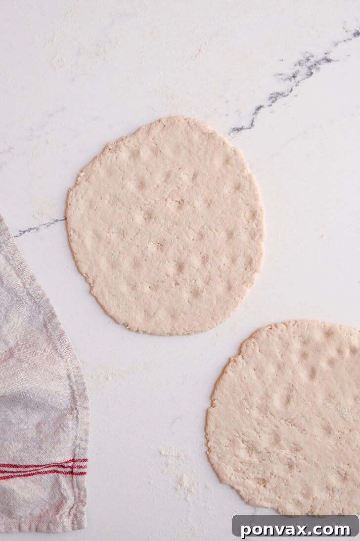 Step 6: Rolling out one portion of dough into a thin, round flatbread shape.