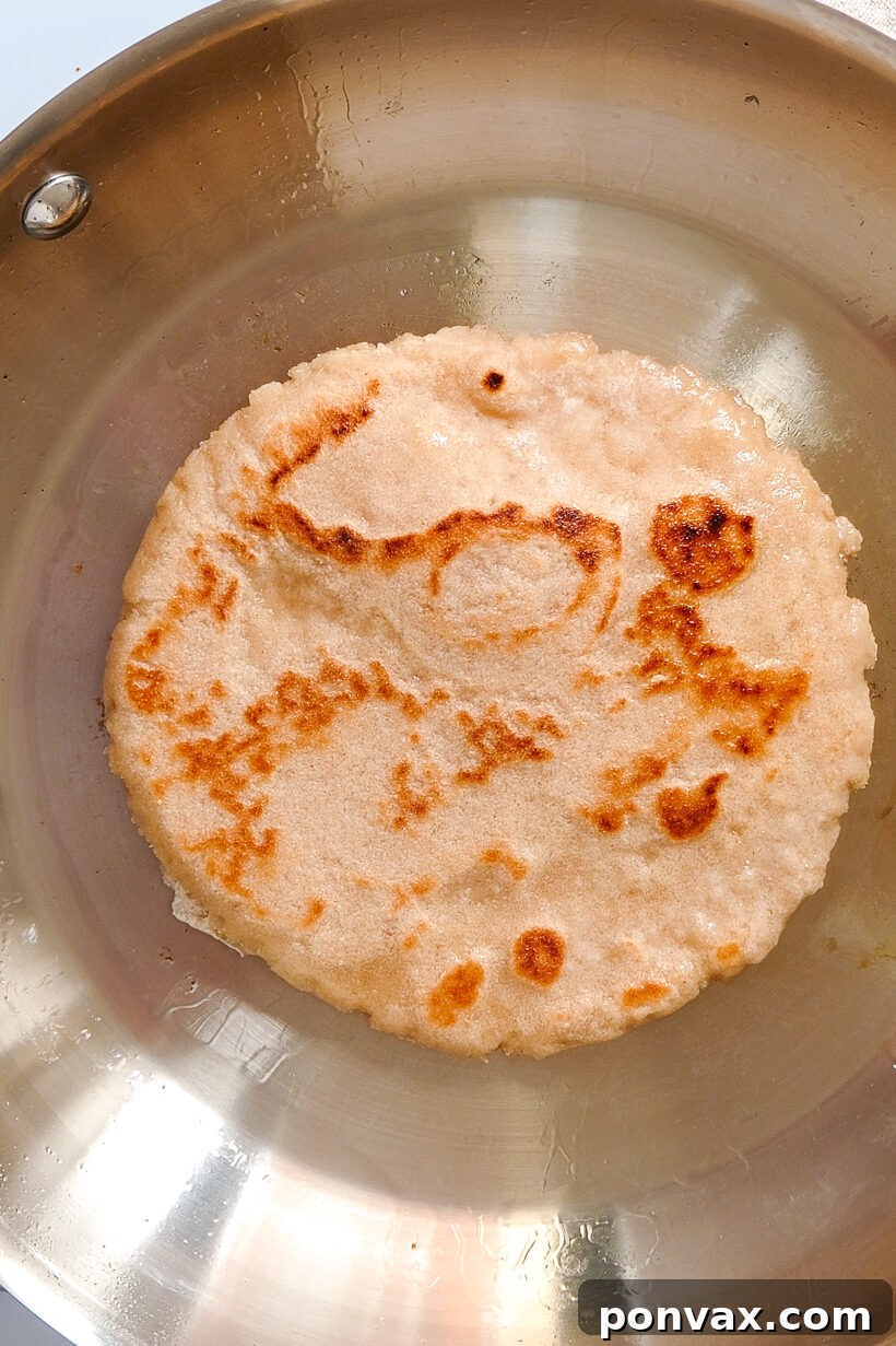 Step 8: Cooking flatbread on a hot skillet, showing characteristic bubbles forming.