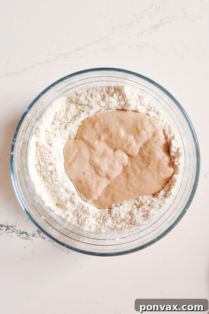 Step 3: Gradually adding the wet psyllium and sourdough mixture to the dry ingredients.