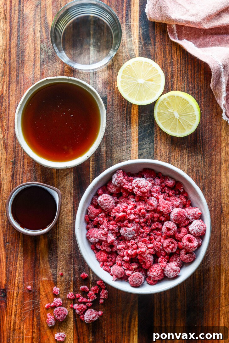 Close-up shot of the vibrant pink homemade raspberry syrup being poured from a small saucepan into a fine-mesh sieve, highlighting the process of straining for a smooth consistency.