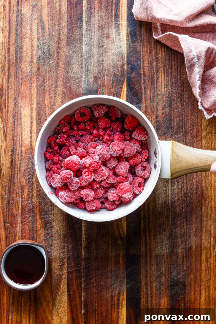 First step of making raspberry syrup: fresh raspberries, water, and sweetener combined in a saucepan, ready to be simmered.