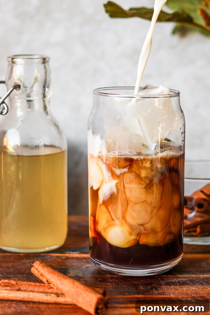 Dairy-free oat milk being poured into iced coffee sweetened with homemade horchata syrup, inspired by Starbucks horchata shaken espresso.