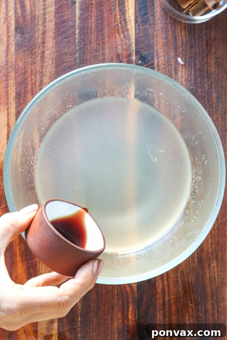 A hand pouring the finished horchata syrup into a decorative glass bottle.