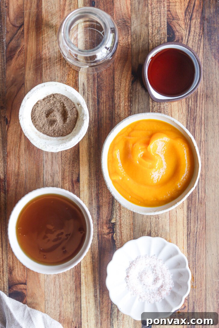 Various ingredients for sugar-free pumpkin spice syrup laid out, including pumpkin puree, pumpkin pie spice, and sugar-free maple syrup.