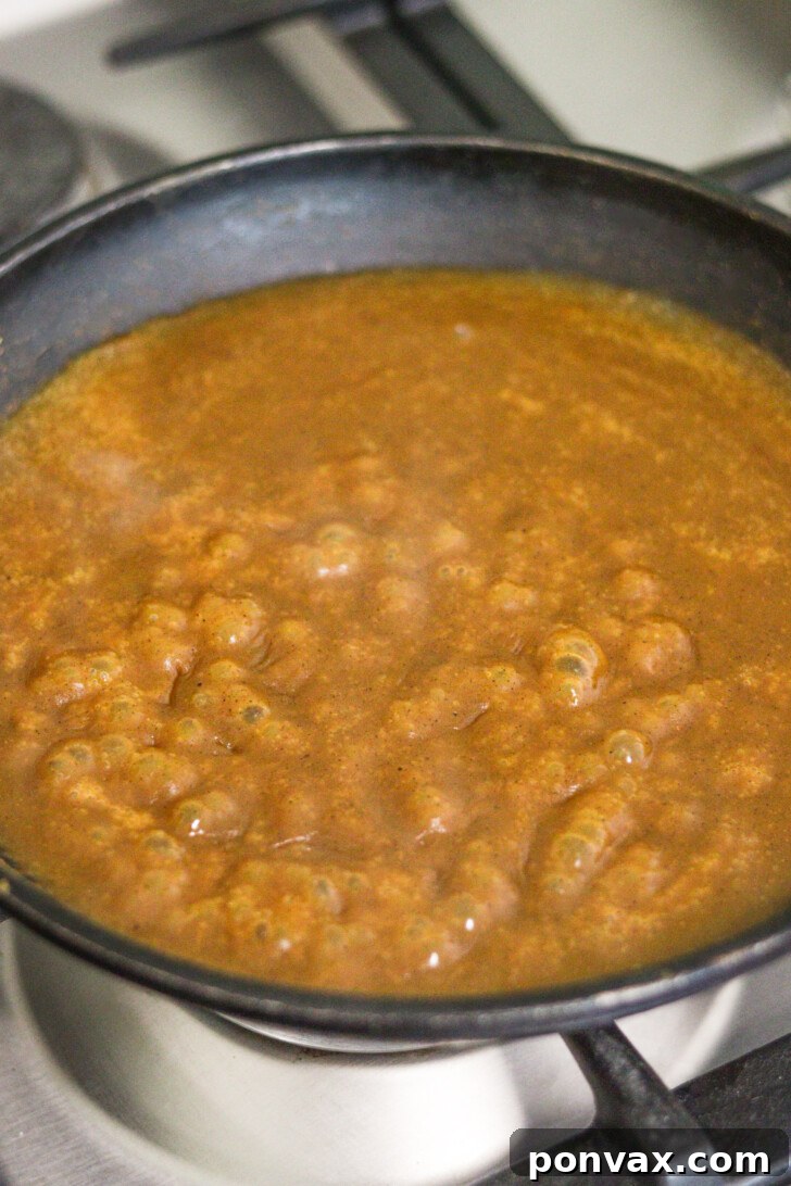 Step 3: Sugar-free maple syrup and water added to the pumpkin mixture in the saucepan.