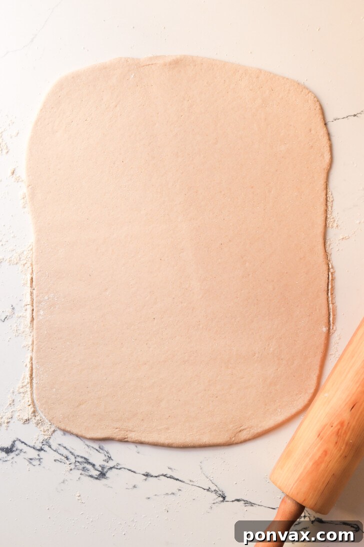 Irresistible Gluten-Free Sourdough Cinnamon Buns 11 Cinnamon sugar filling being spread over the dough.