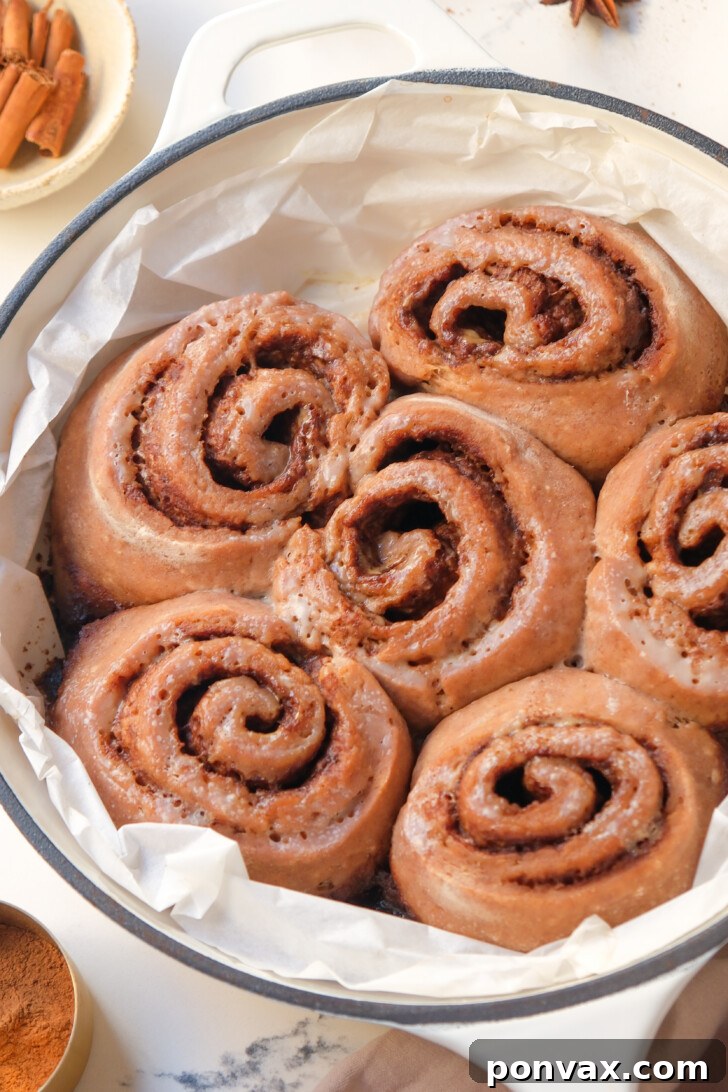 Irresistible Gluten-Free Sourdough Cinnamon Buns 19 Two soft gluten-free sourdough cinnamon rolls on a baking sheet.
