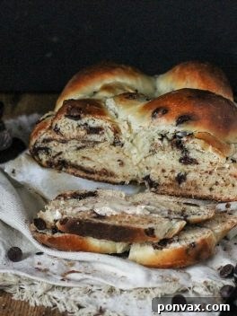 A stunning Chocolate Chip Challah, braided to perfection, with a golden crust and hints of melted chocolate, resting on a wooden surface.