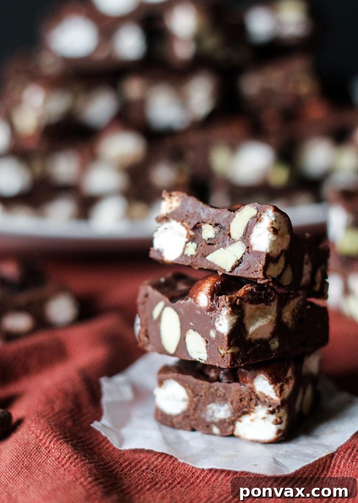 Perfectly set, creamy Rocky Road Fudge being sliced into individual squares, revealing a beautiful medley of marshmallows and chopped Planters Cocoa Almonds.