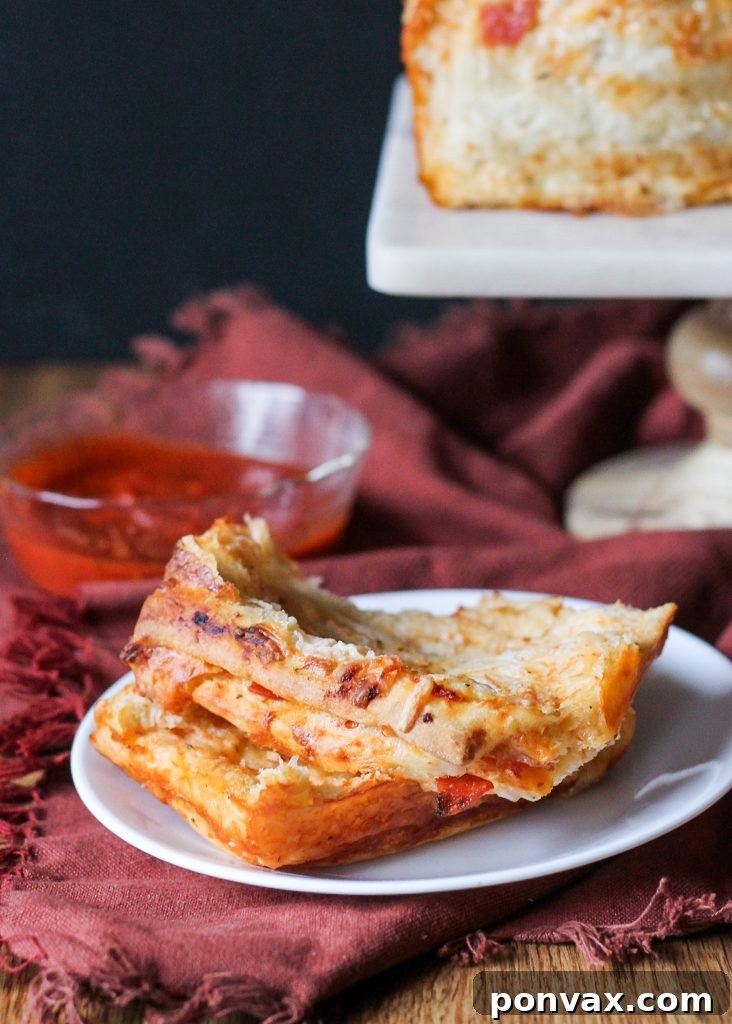 A close-up of a hand pulling a cheesy, pepperoni-filled piece from the Pepperoni Pizza Pull Apart Bread, highlighting the delicious stringy cheese.