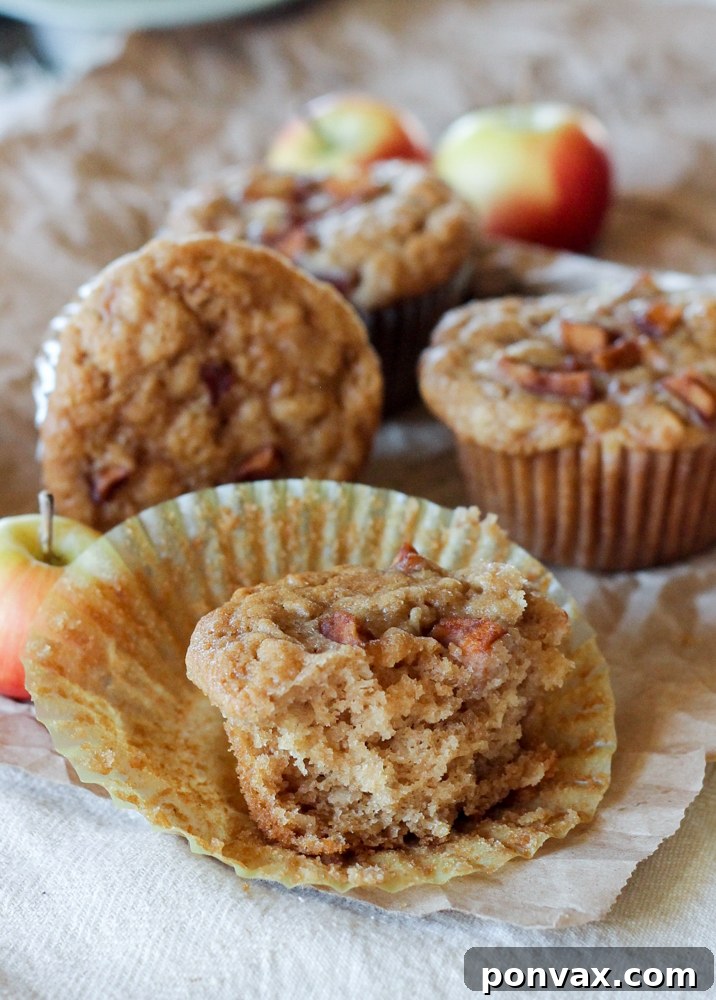 A hand holding a perfectly baked apple oatmeal muffin, showcasing its tender texture and golden-brown top, perfect for a healthy breakfast.