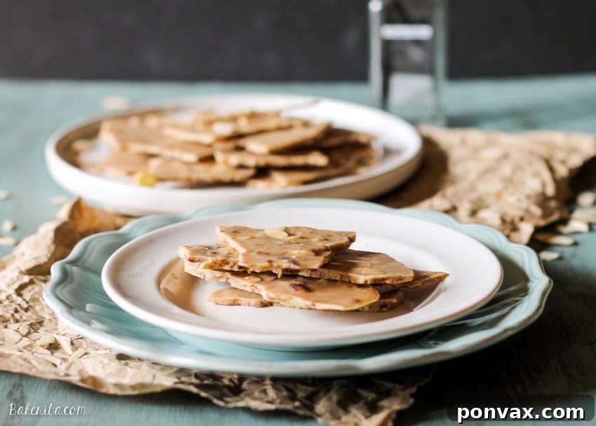 Hand holding a piece of Vanilla Almond Butter Bark, showcasing its perfect break and rich texture.