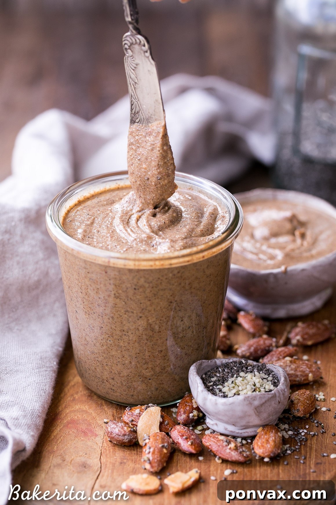 A spoonful of Maple Almond Butter being lifted from a glass jar, showing its creamy texture.