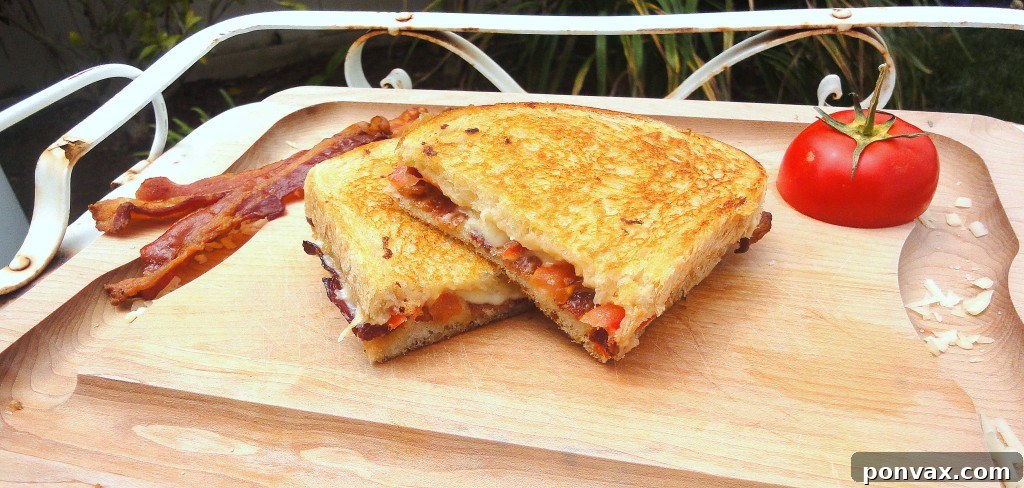 Golden-brown Bacon, Tomato, and Roasted Garlic Grilled Cheese sandwich, sliced in half, revealing melted cheese and flavorful fillings