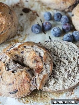 A basket of freshly baked blueberry bagels with some sliced in half, ready to be eaten.