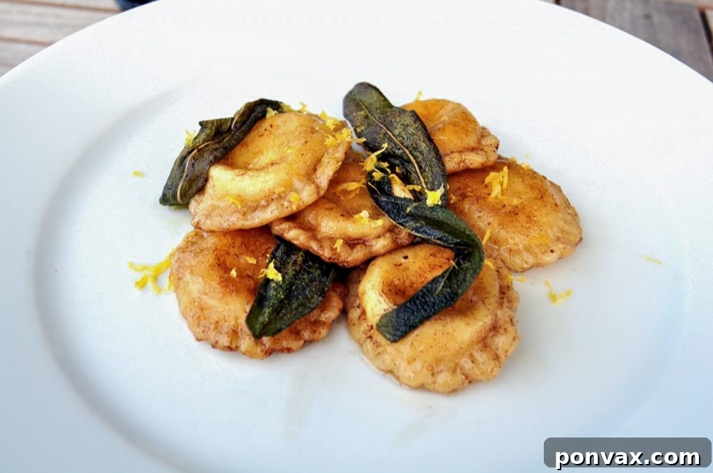 Close-up of golden-brown ravioli resting on a dish, highlighting the delicate pasta and the rich sage brown butter sauce.