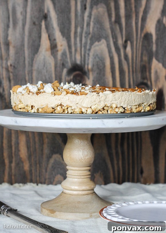 A beautifully sliced piece of No-Bake Peanut Butter Dulce de Leche Cheesecake on a white plate, revealing the distinct layers of the crunchy popcorn crust and the smooth, creamy filling. The top is lightly drizzled with dulce de leche and garnished with more popcorn, highlighting its readiness to be enjoyed.