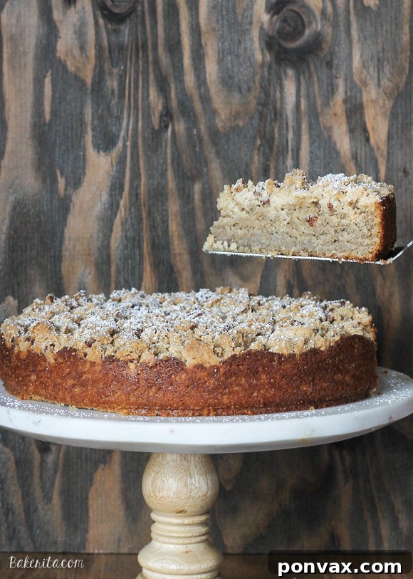 Plant-Based Banana Streusel Cake 4 A generous slice of Dairy-Free Banana Crumb Cake, showcasing the fluffy, moist interior of the cake and the abundant, textural crumb topping with visible chopped pecans. A delightful treat for any occasion.