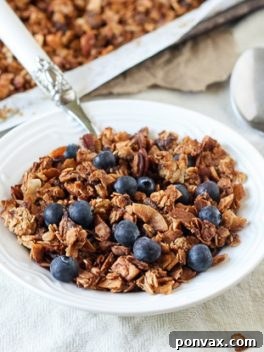 Tropical Banana Coconut Granola 6 A vibrant bowl of freshly prepared Banana Coconut Granola, featuring visible banana chunks, coconut, and pecans.