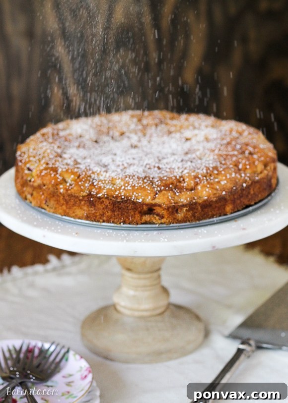 A vibrant close-up of a slice of Caramel Rhubarb Cake, showcasing its moist, fluffy crumb and the gentle pink hues of the cooked rhubarb peeking through the rich, golden caramel swirls. The image emphasizes the cake's tender texture and delicious, inviting appearance.