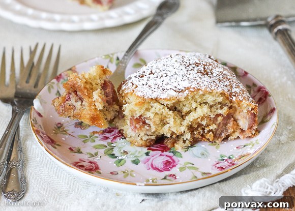 A top-down view of the freshly baked Caramel Rhubarb Cake, showing the beautiful crackled, golden-brown surface and the generous, inviting swirl of caramel peeking through. The image is styled to evoke warmth and homemade goodness, inviting you to take a slice.